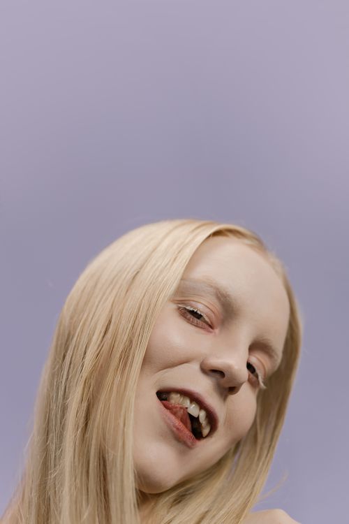 Free Close-up portrait of a blonde woman with expressive pose on purple backdrop. Stock Photo