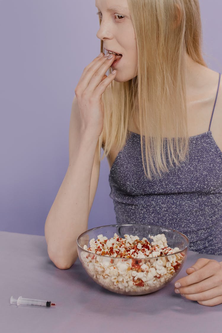 A Woman In Gray Top Eating Popcorn