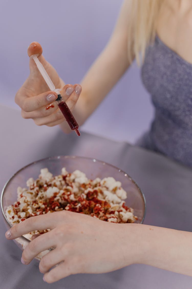 A Person Holding A Syringe With Red Liquid