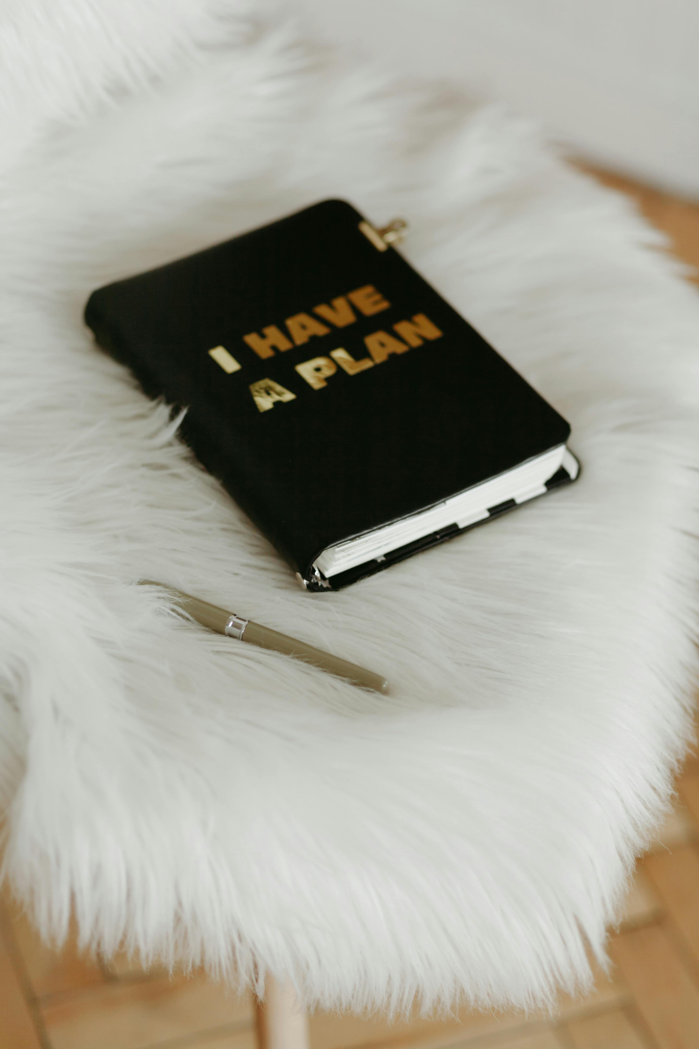 black and gold book beside white click pen