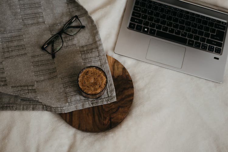 A Coffee And Eyeglasses On The Bed 