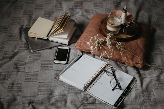 A cozy scene featuring a planner, coffee, smartphone, and books on a bed, perfect for a relaxing morning routine.
