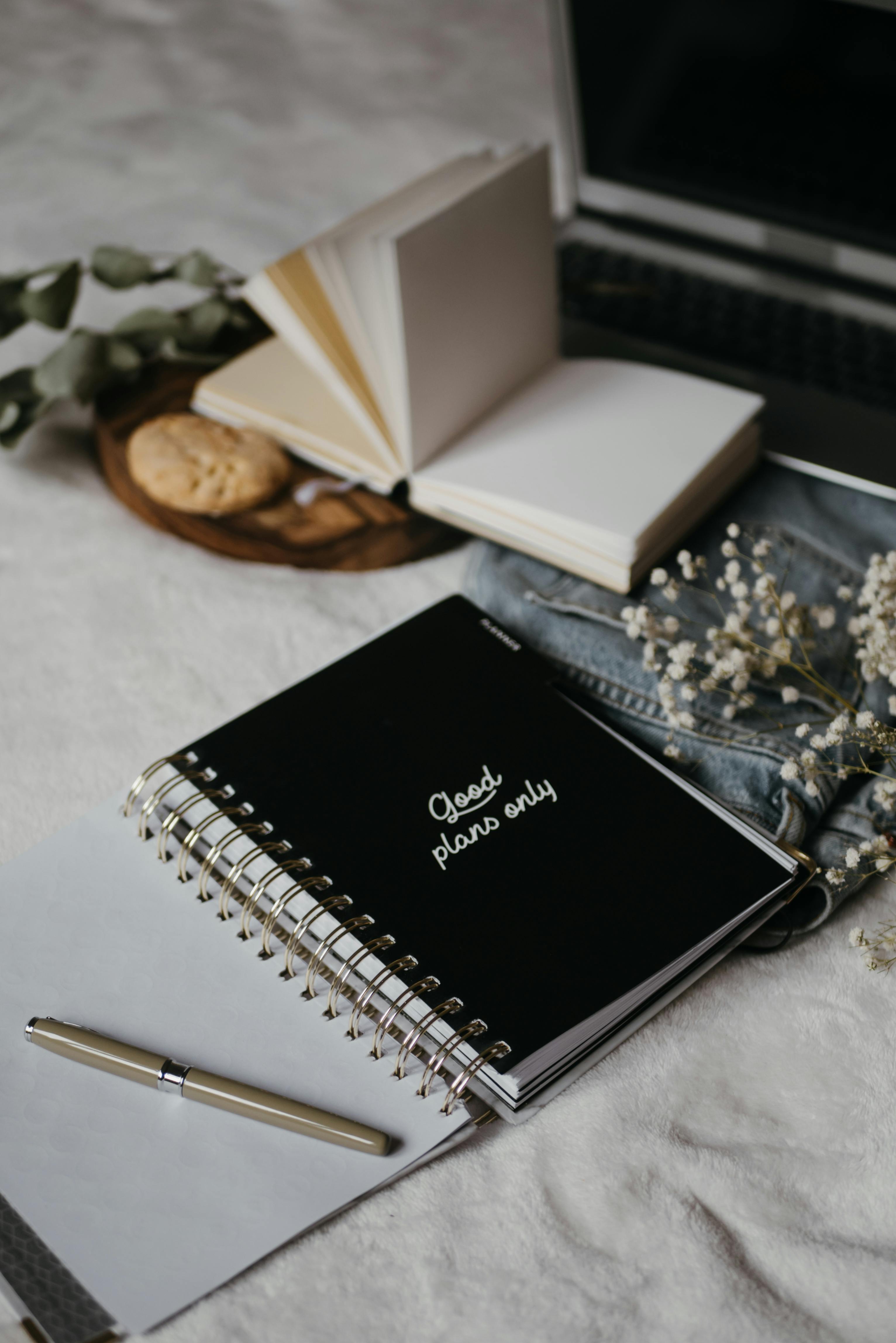 black notebook beside white click pen