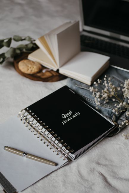 Inviting workspace setup featuring notebooks, a laptop, and cookies for a cozy work-from-home feel.