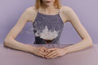 一名女子优雅地坐着，在紫色背景前喝着烟熏马提尼，散发着神秘和魅力