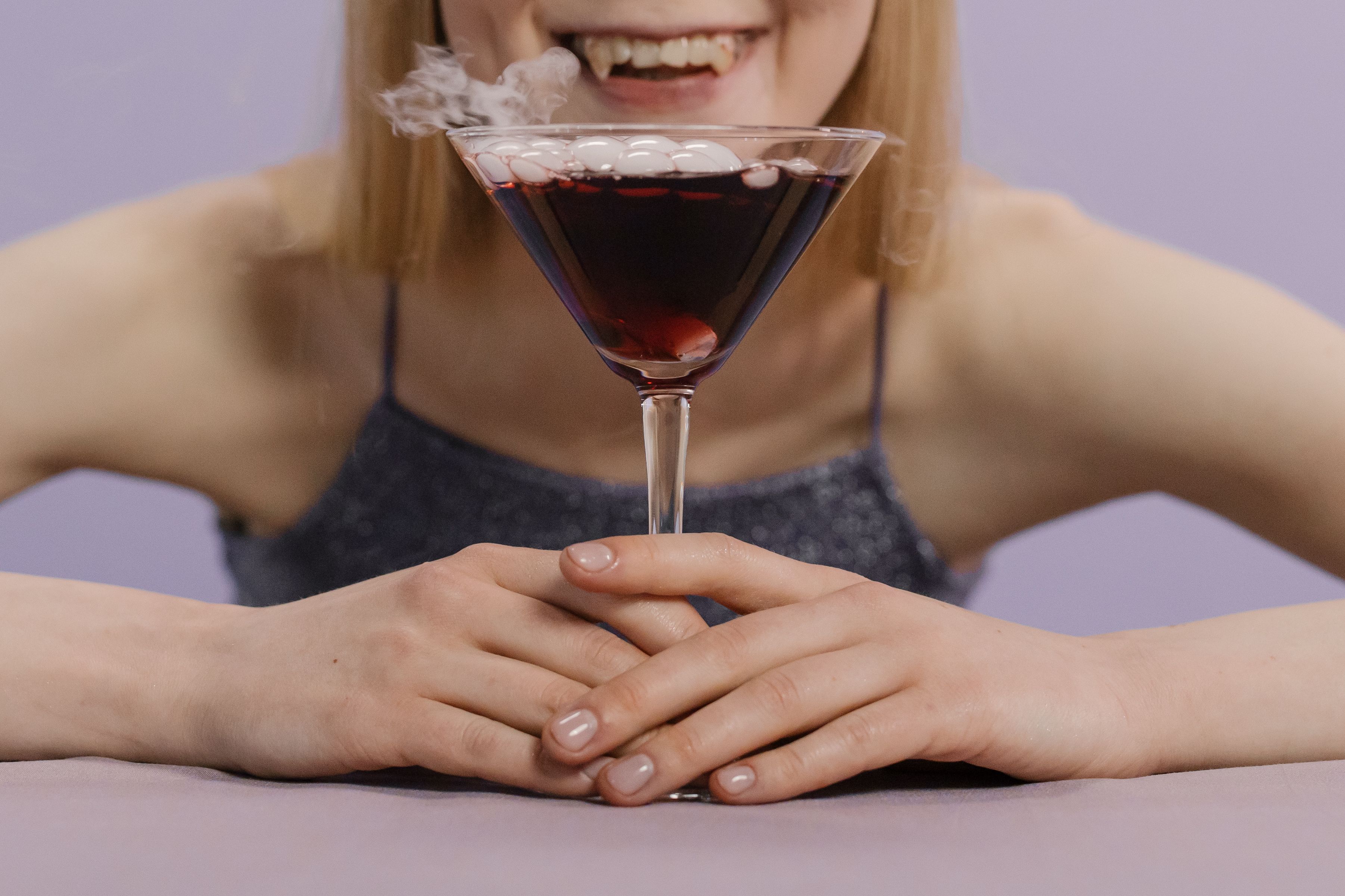 一名女子正在用马提尼杯享用一杯带有干冰的怪异万圣节鸡尾酒