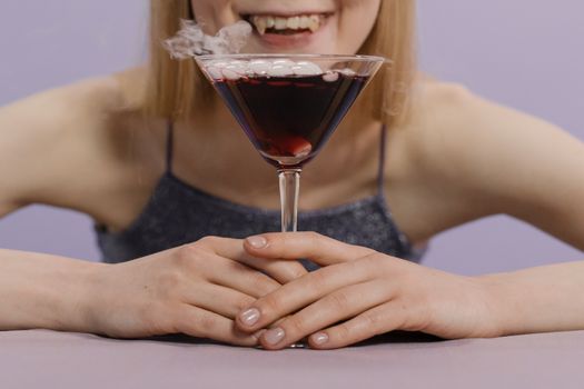 一名女子正在用马提尼杯享用一杯带有干冰的怪异万圣节鸡尾酒