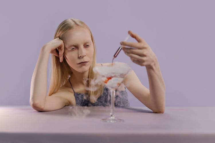 Woman Holding A Syringe Infusing Color Into A Wine Glass