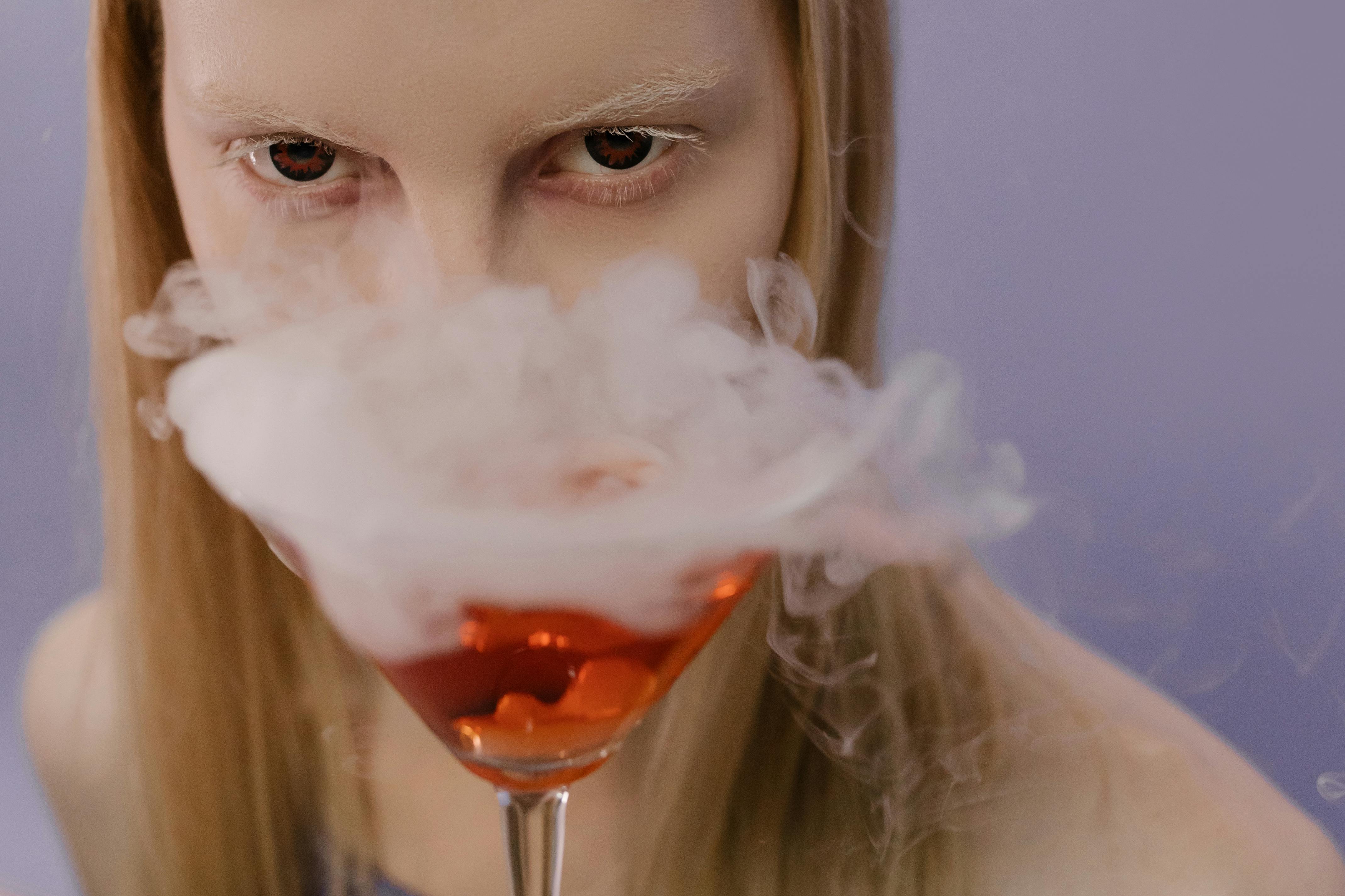 Mysterious portrait of a woman with a smoking cocktail and vampire-like appearance.