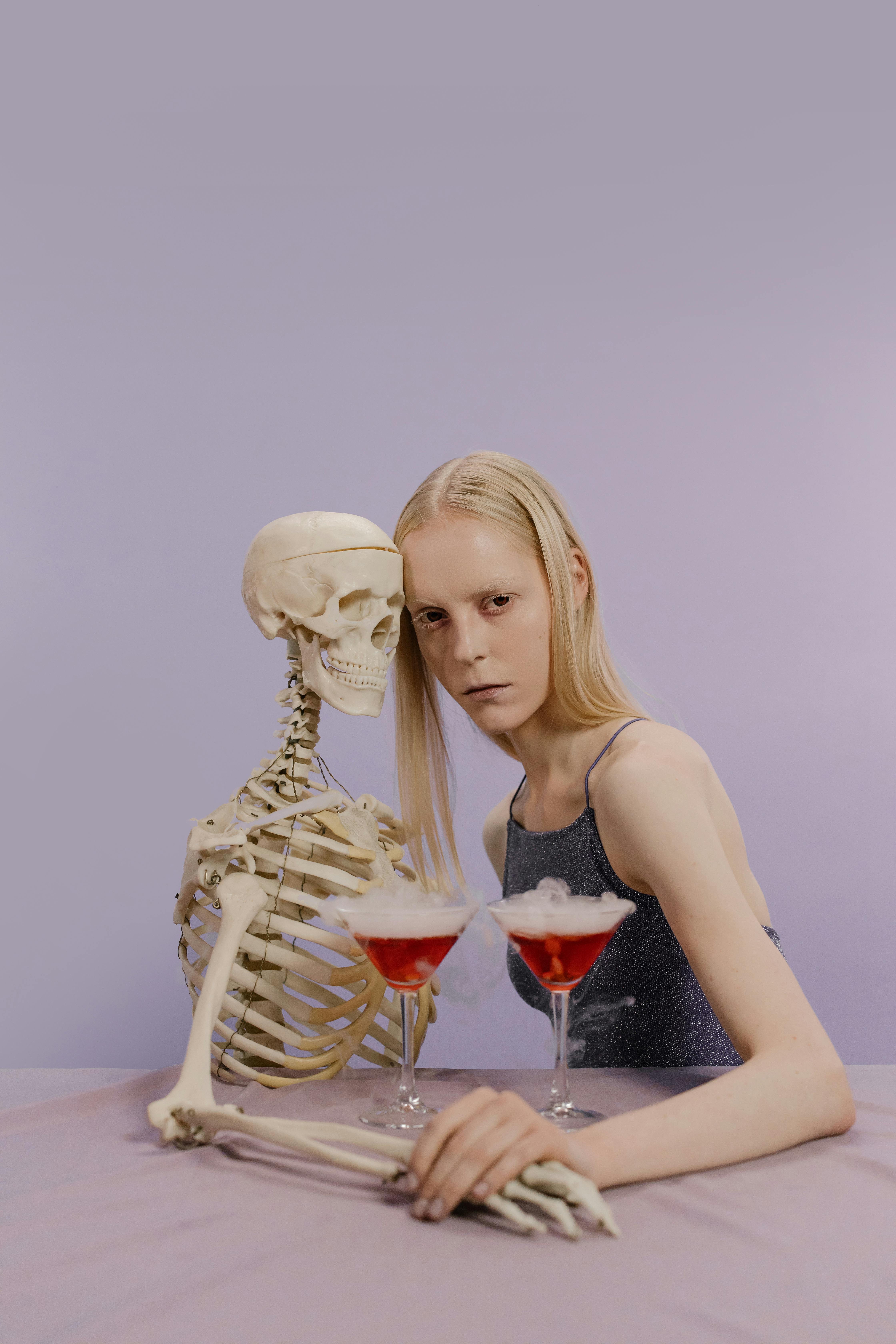 woman in gray tank top leaning her head on a skeleton