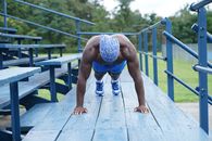Man in Blue Shorts and White Sneakers Standing on Wooden Bridge