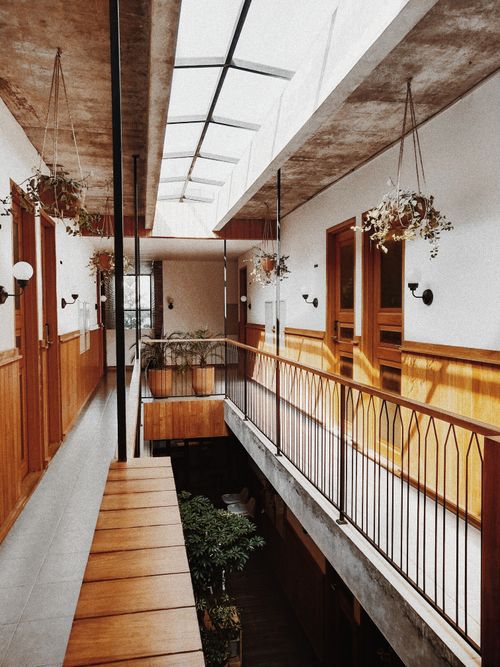 Free Modern indoor hallway with skylight, wooden accents, and hanging plants. Stock Photo