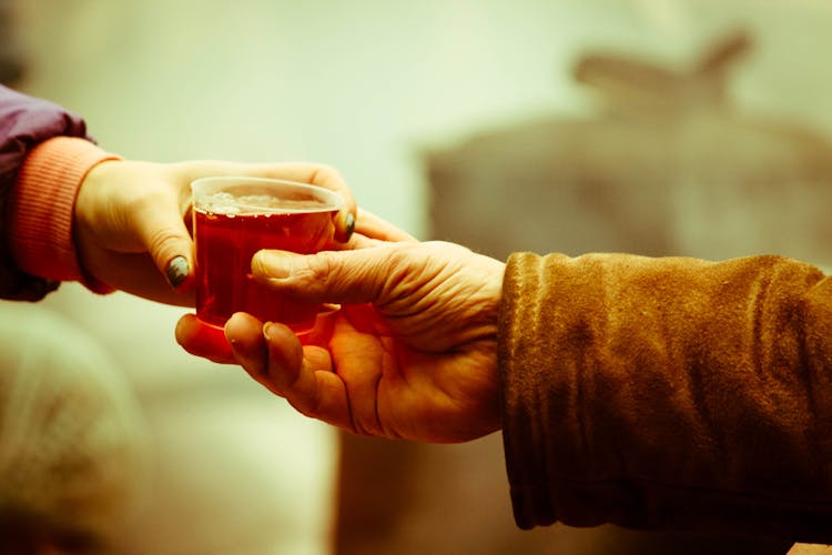 People Sharing Cup Of Hot Tea Outdoors