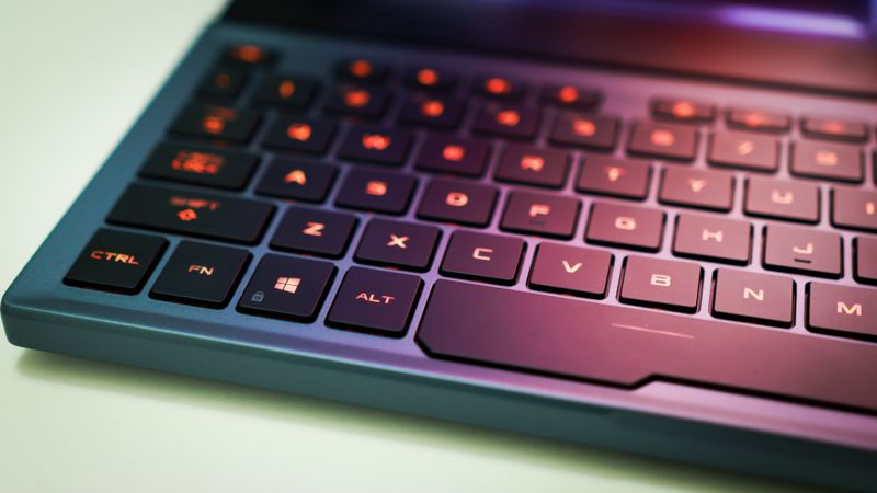 Close-up of a laptop keyboard with glowing orange backlit keys, emphasizing modern technology.