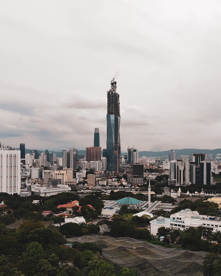 The Merdeka Tower Amidst City Buildings In Kuala Lumpur, Malaysia