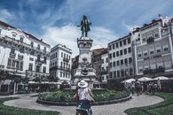 Monumental statue in a bustling Porto square, capturing local life and architecture.