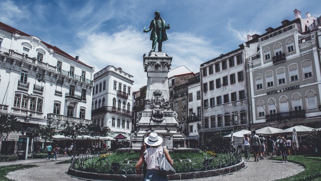 Portugal, Monumental statue in a bustling Porto square, capturing local life and architecture.