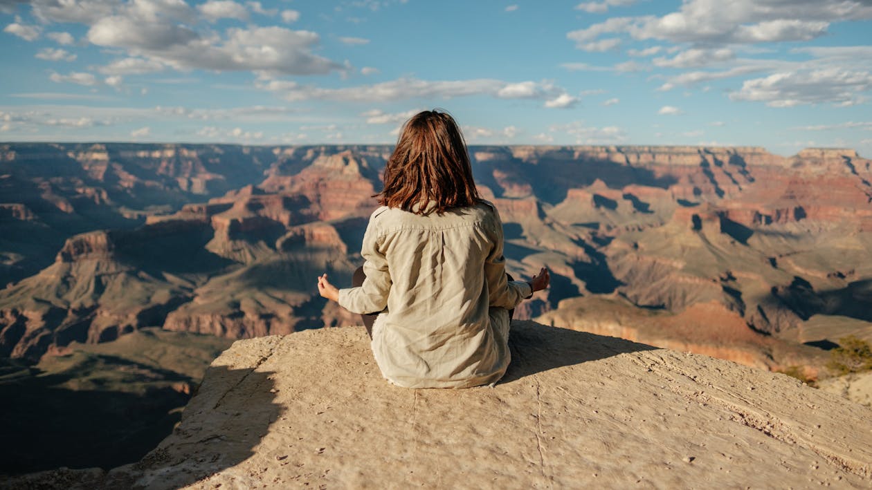 Free Woman Sitting on Mountain Top Doing Meditation Stock Photo