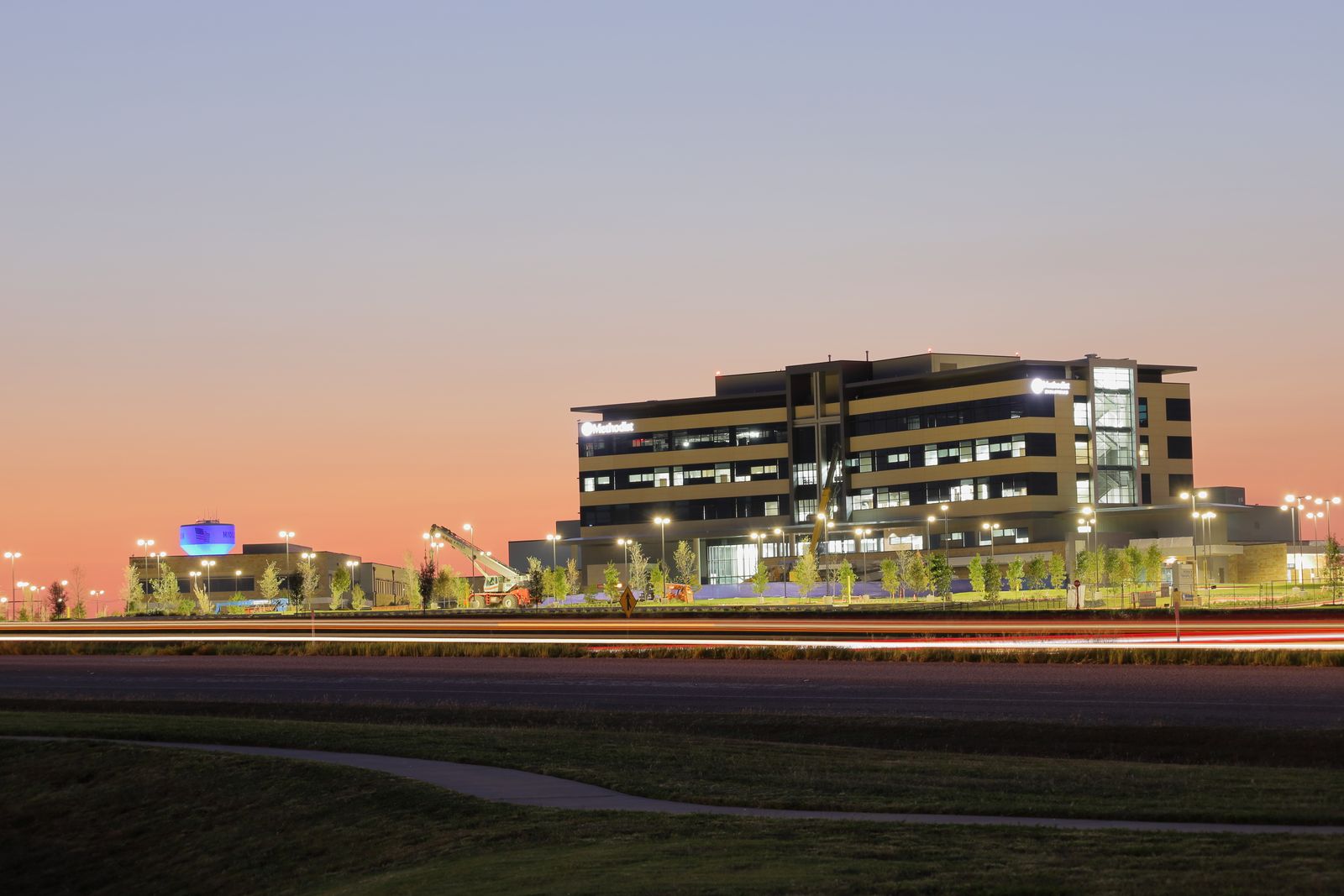 Illuminated hospital campus building in the evening representing coordinated multi-building vertical transportation