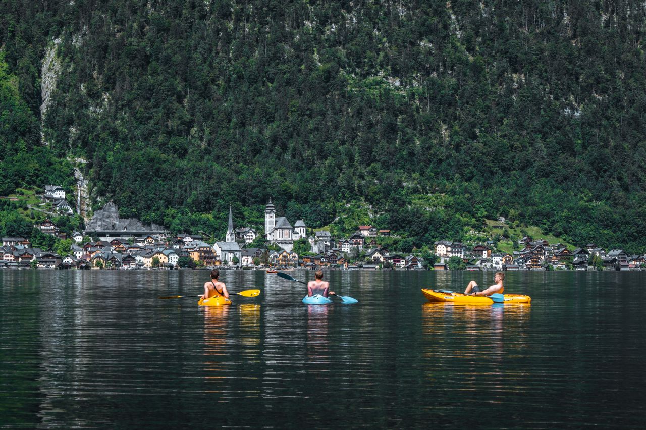 three kayakers enjoying a day out on lake hallstatt with scenic villag