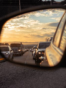 Cars in a traffic jam during sunset, reflecting in a vehicle's side mirror.