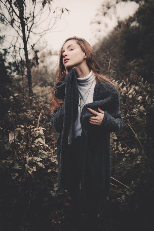 Donna In Cappotto Nero Che Sta Vicino Agli Alberi Marroni