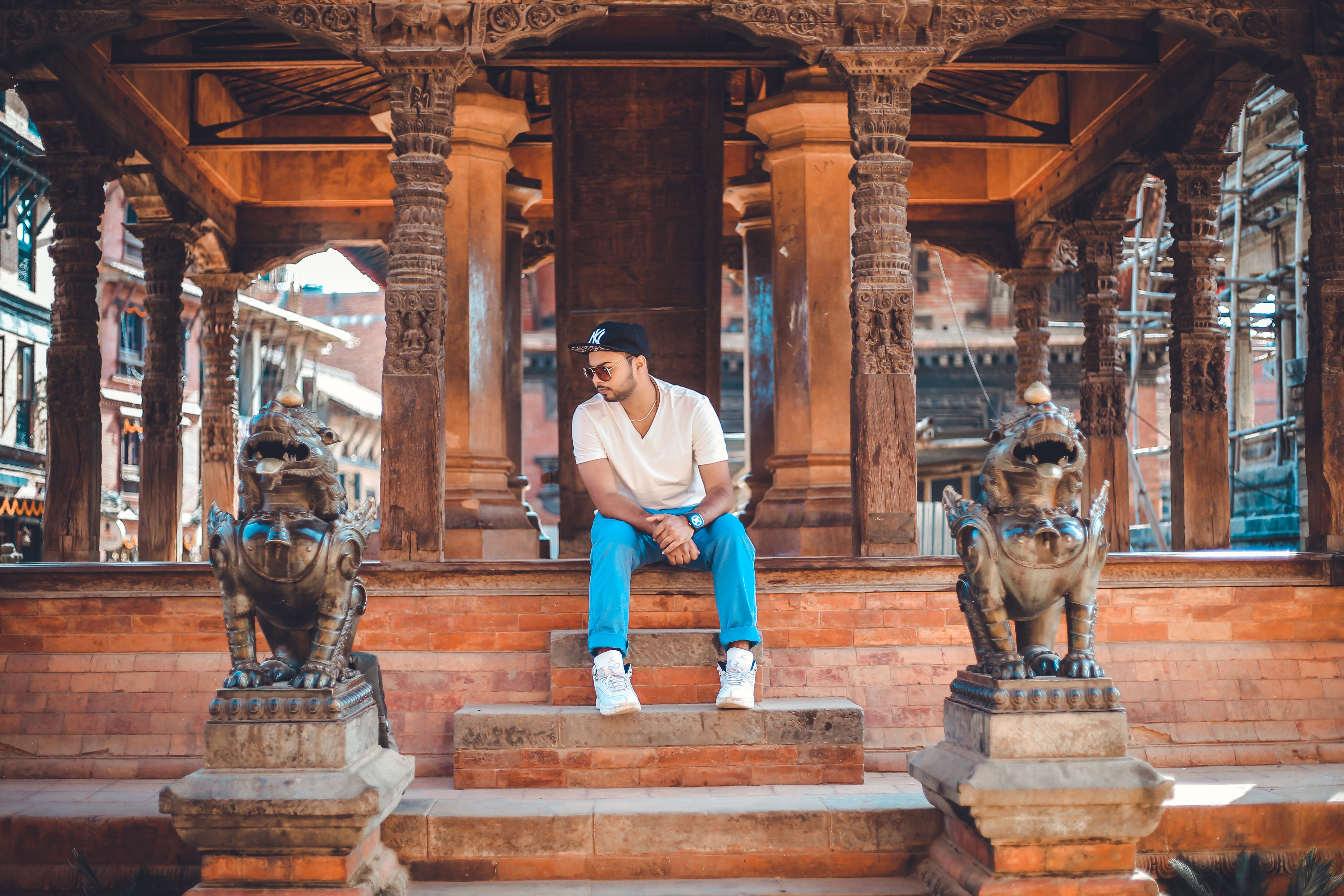 Stylish young man in sunglasses sitting on temple steps in Kathmandu, Nepal.