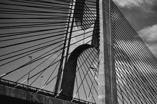 Free Close-up view of a suspension bridge's architectural design in black-and-white, showcasing cables and structure. Stock Photo