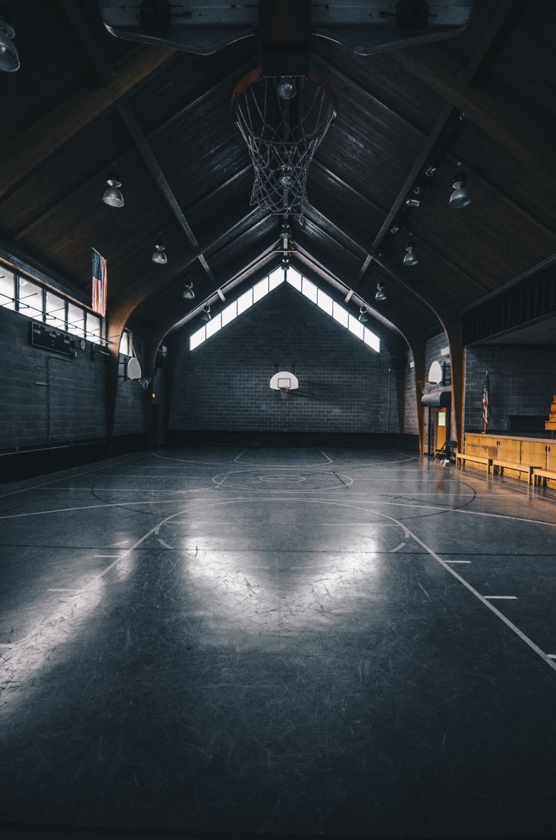 Dimly lit empty indoor basketball court — photo by Karl Solano on Pexels