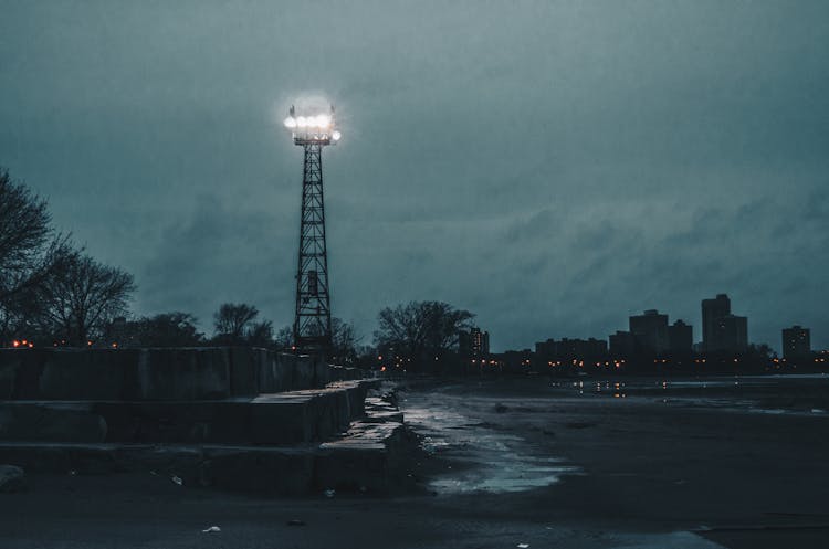 Electricity Pole Near City At Night 