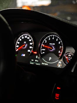 Detailed view of a car dashboard featuring illuminated speedometer, RPM gauge, and various indicators.