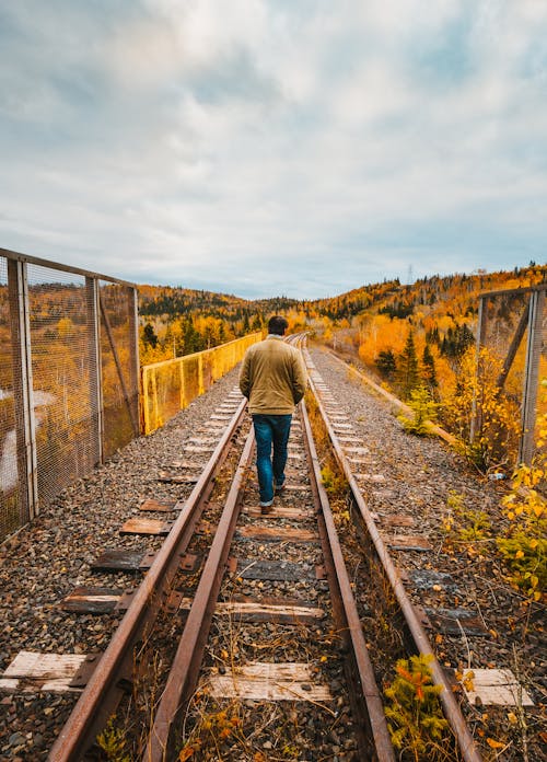 Back View of a Man Walking in the Train Tracks