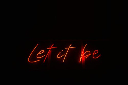 Free Vibrant neon sign displaying 'Let it be' on a black background, conveying positivity. Stock Photo