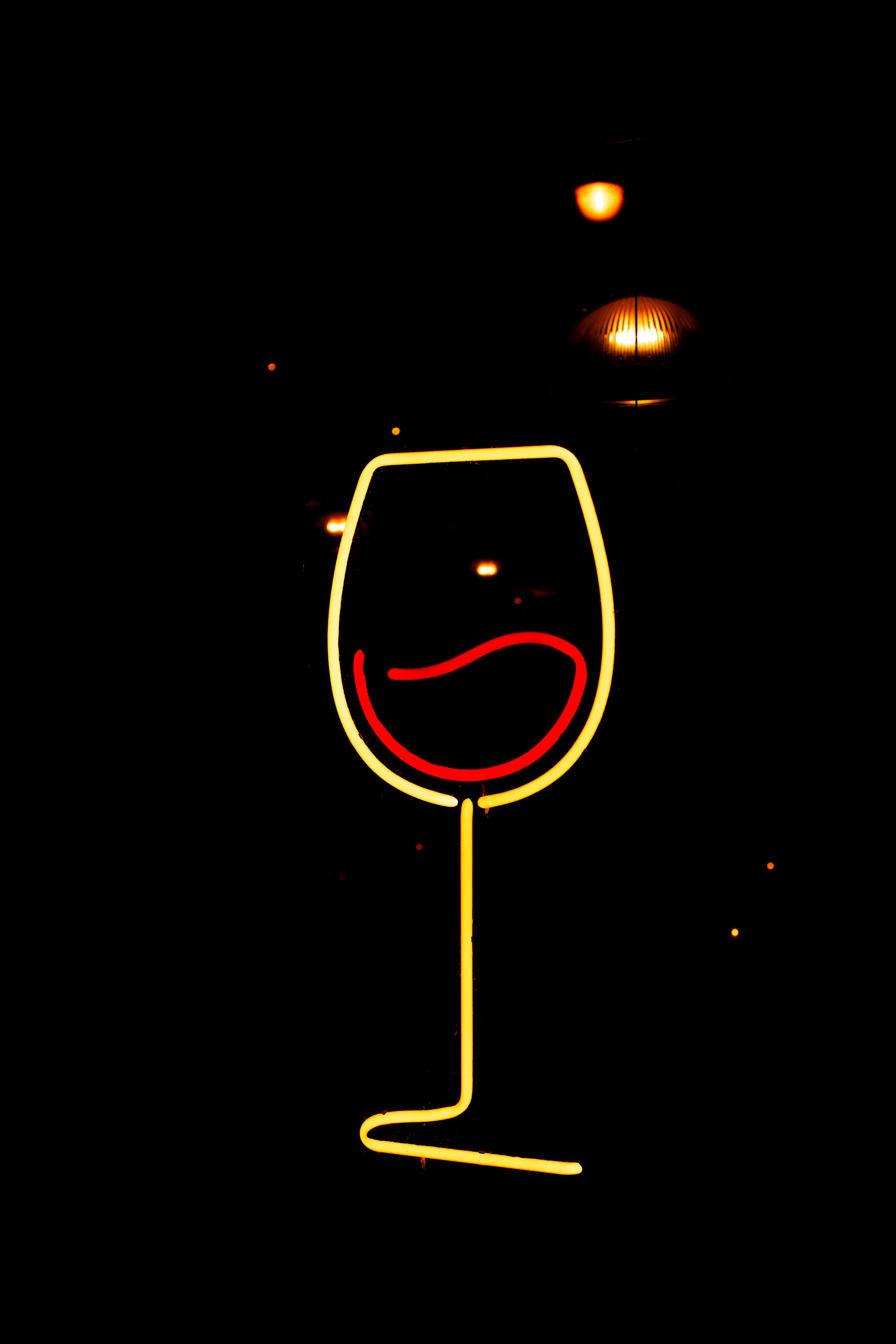 黑色背景上，霓虹灯标志插图描绘了一个酒杯，简约而明亮