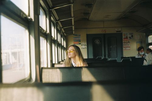 Free Young female with long hair in sunglasses sitting on passenger seat in train wagon and looking at window during journey in daytime Stock Photo