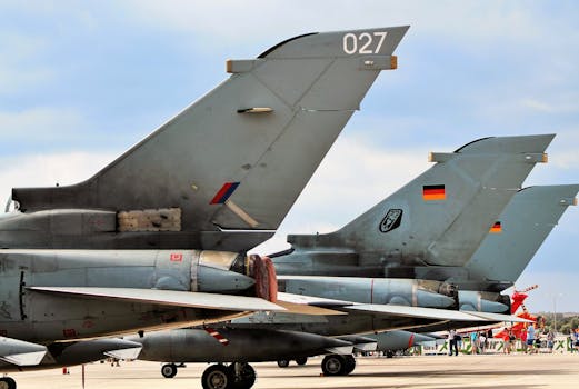 Close-up view of military aircraft parked on an airport runway, showcasing tail sections.
