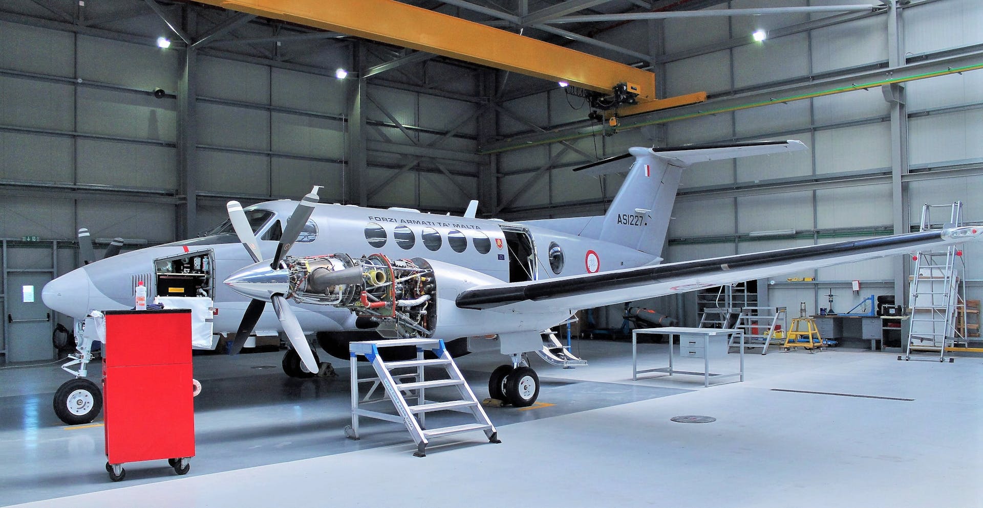 Aircraft undergoing maintenance in a spacious modern hangar.