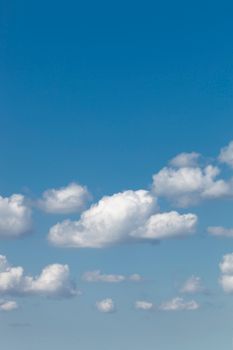 Bright blue sky filled with fluffy white cumulus clouds on a sunny day.