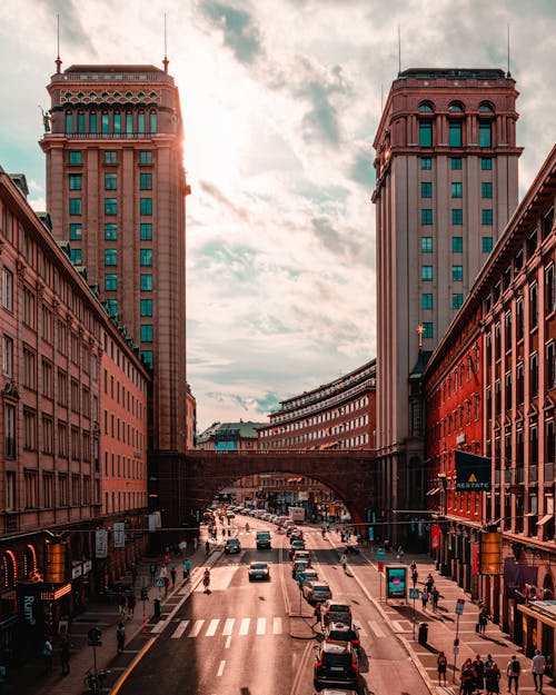 Cars Parked Beside Brown Concrete Building Under Cloudy Sky