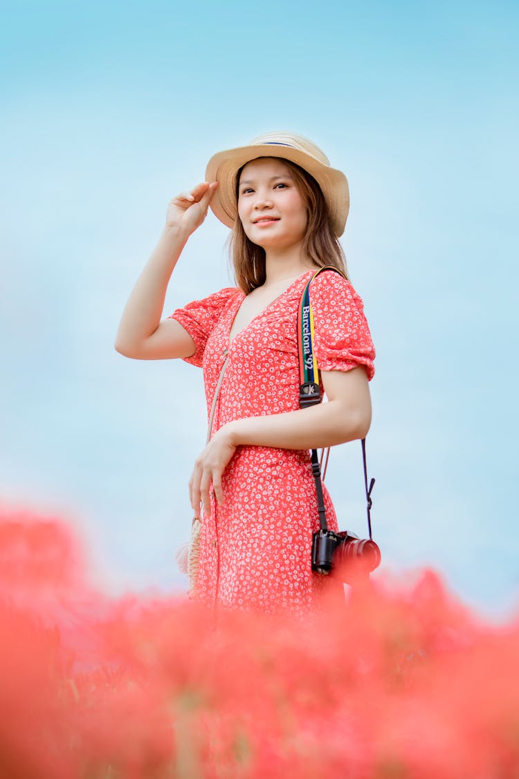 A Woman Wearing Red Floral Dress Holding A Camera On Her Shoulder