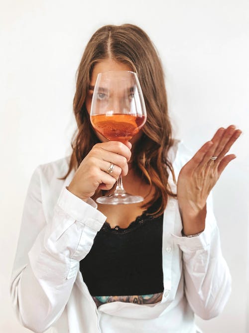 Woman in White Long Sleeve Shirt Holding Wine Glass