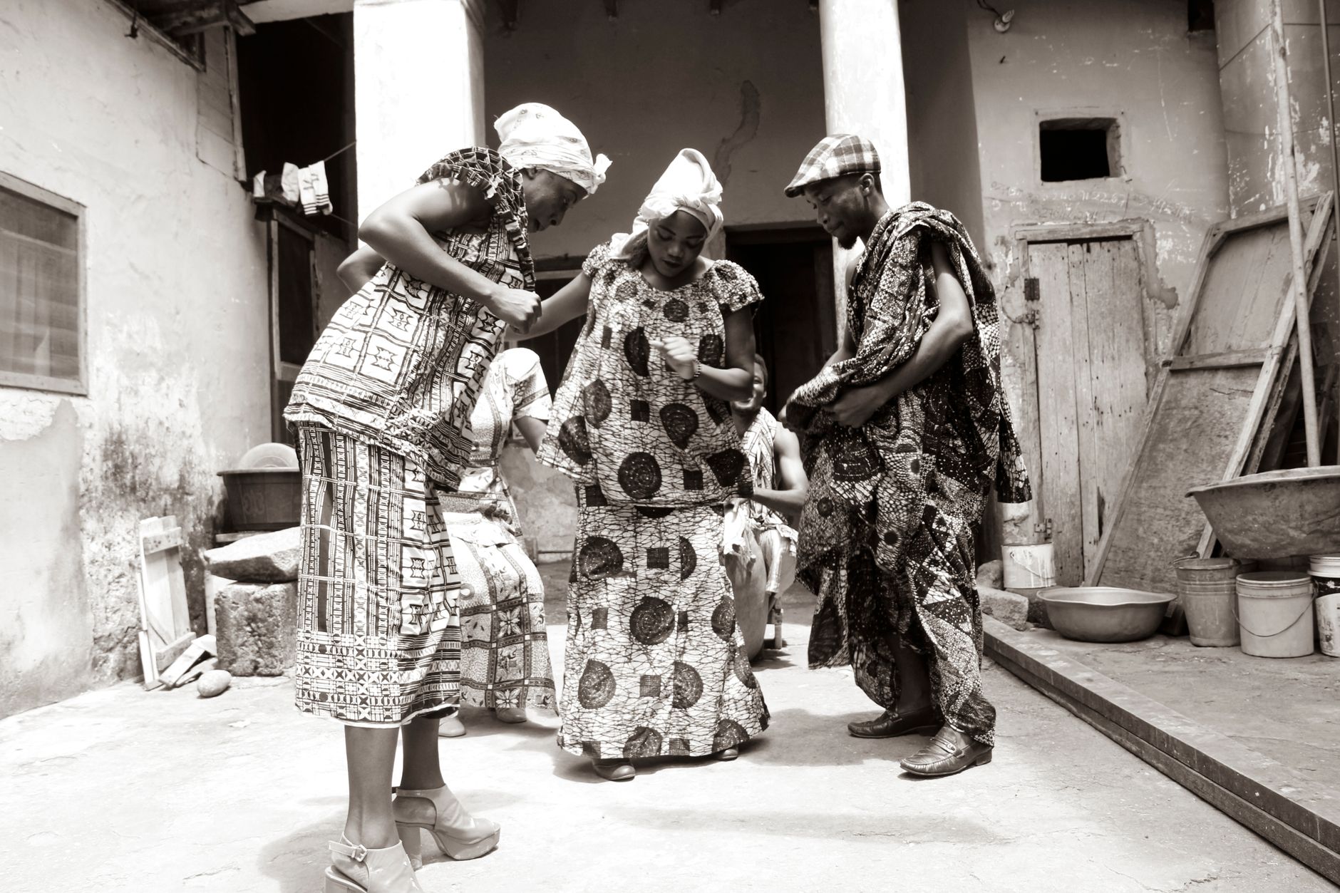 Joyful celebration of traditional Ghanaian dance by adults in vibrant attire outdoors.