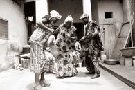 Joyful celebration of traditional Ghanaian dance by adults in vibrant attire outdoors.