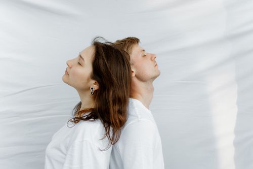 Free A serene portrait of a man and woman posed back to back on a white background. Stock Photo