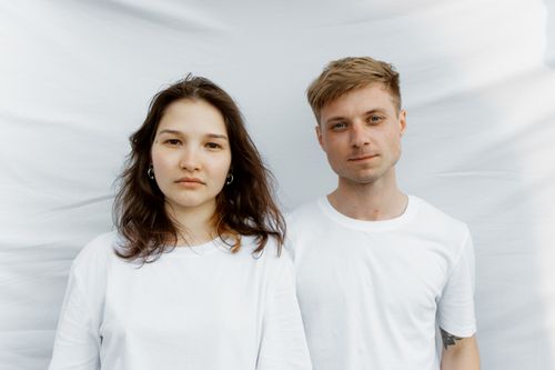 Free Portrait of an interracial couple in white shirts against a plain background, conveying simplicity and love. Stock Photo