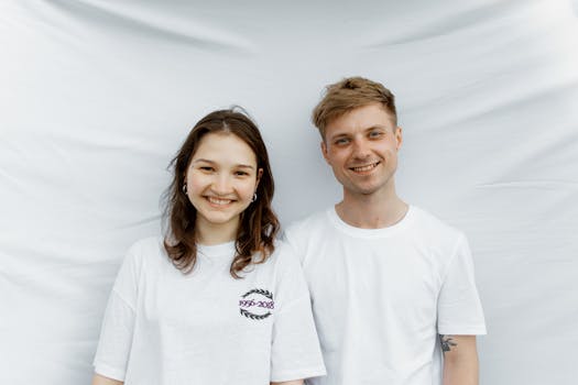 一对穿着白衬衫的夫妇在白色背景下微笑，洋溢着随意而友好的氛围