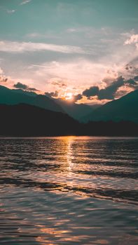 Tranquil view of a mountain lake during sunset with vibrant sky and calm waters.