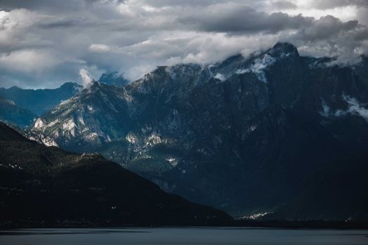 Picturesque view of rough ridge of mountain near hill slope and lake under cloudy sky