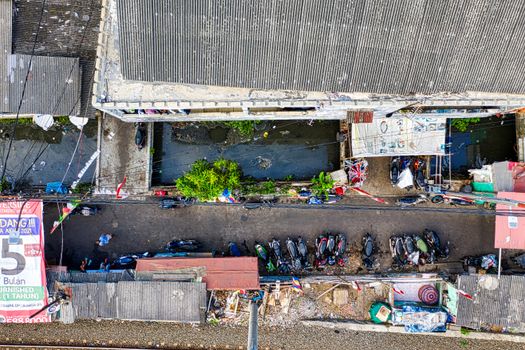 Drone shot of an urban alley in Jakarta with parked motorcycles and rooftops.