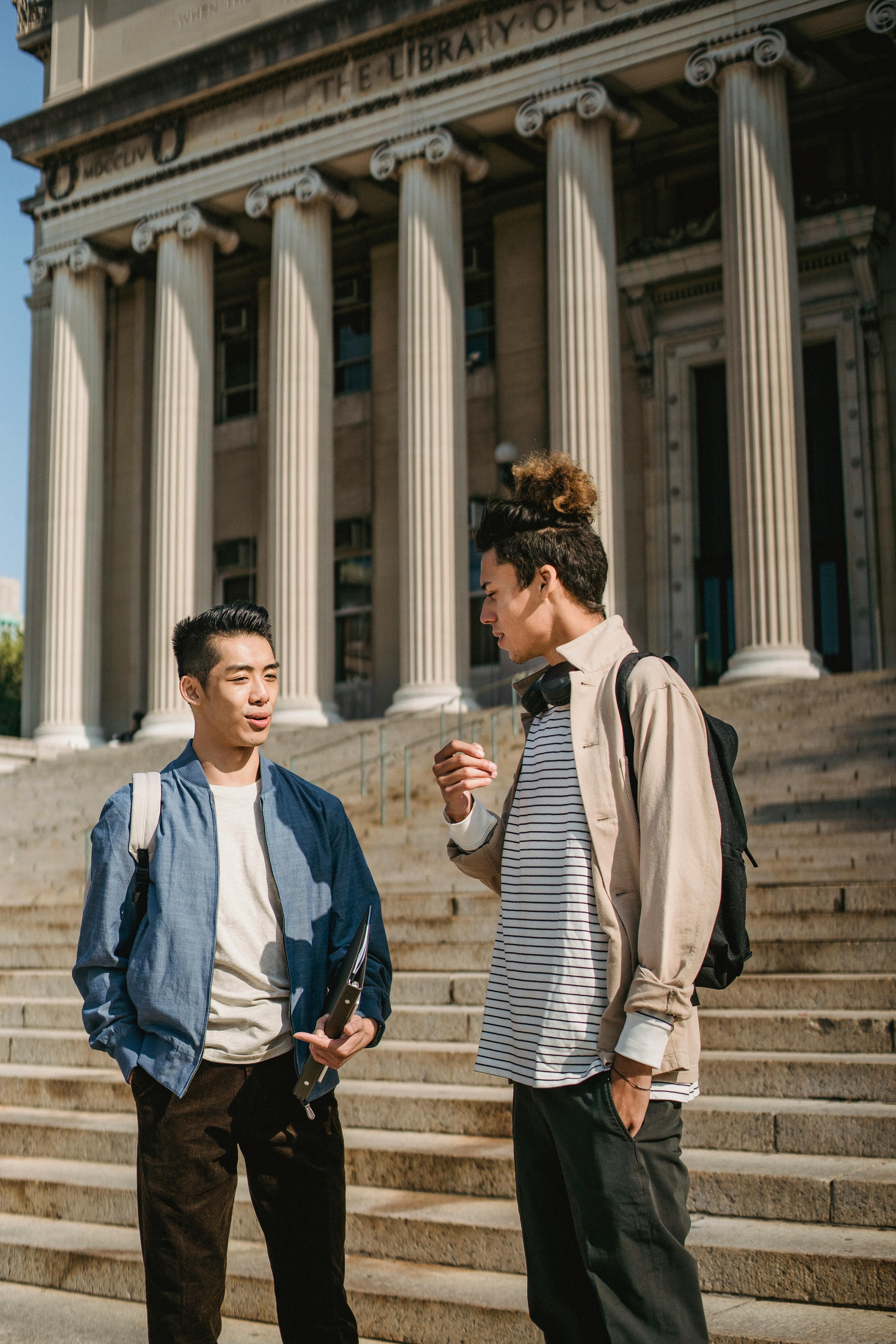 multiethnic friends standing on concrete steps of university